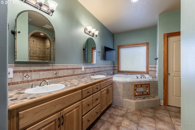 bathroom with a bathing tub, vanity, a textured ceiling, and tasteful backsplash