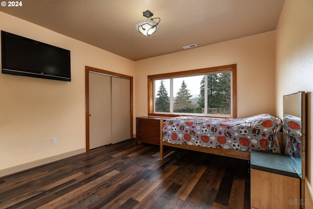 bedroom with dark hardwood / wood-style flooring and a closet