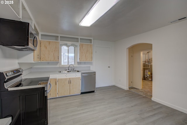 kitchen with sink, light hardwood / wood-style flooring, gas water heater, light brown cabinetry, and appliances with stainless steel finishes