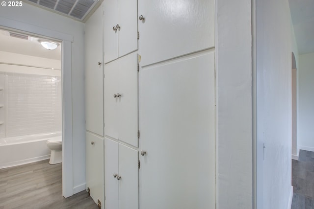 bathroom with toilet, hardwood / wood-style floors, and tub / shower combination