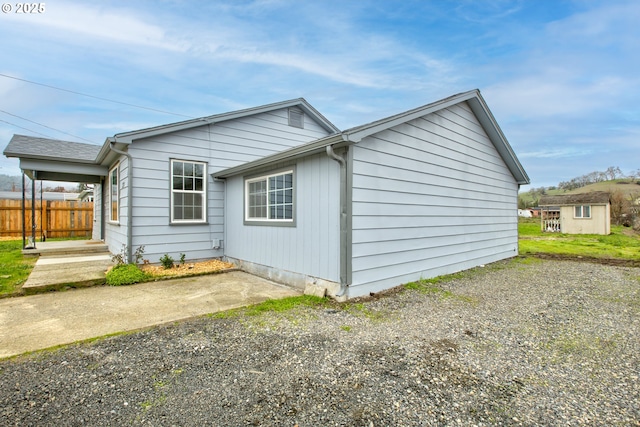 view of home's exterior with a patio area and an outbuilding