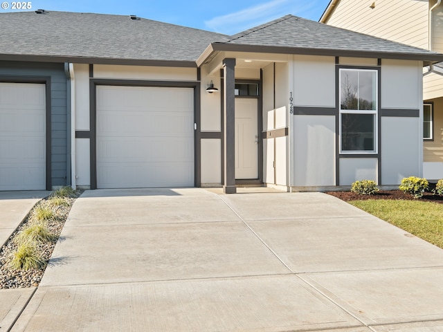 view of front of home featuring a shingled roof, concrete driveway, an attached garage, and stucco siding