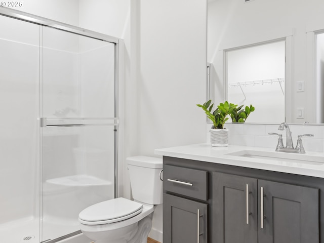 bathroom featuring toilet, a shower stall, a walk in closet, and vanity