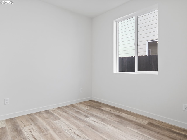 empty room featuring light wood finished floors and baseboards