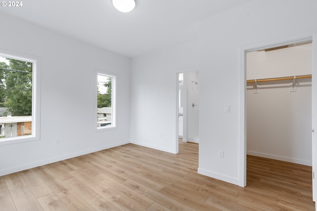 unfurnished bedroom with light hardwood / wood-style floors, a closet, and a walk in closet