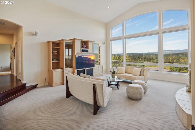 living room featuring high vaulted ceiling and light colored carpet