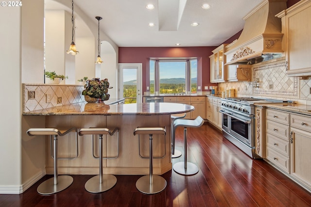 kitchen with custom range hood, a kitchen bar, range with two ovens, and light stone counters