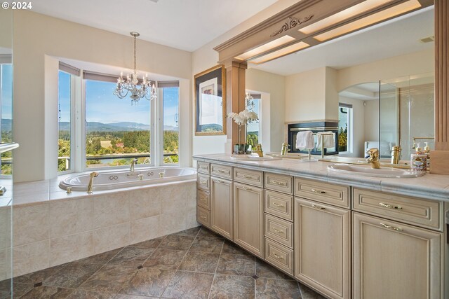 bathroom featuring tiled tub, vanity, a healthy amount of sunlight, and a mountain view