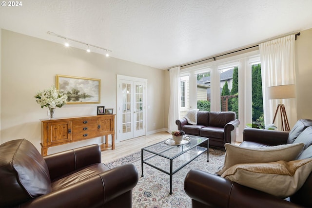 living room with french doors, a textured ceiling, and light hardwood / wood-style floors