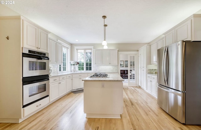 kitchen with a kitchen island, light wood-type flooring, white cabinetry, and stainless steel appliances