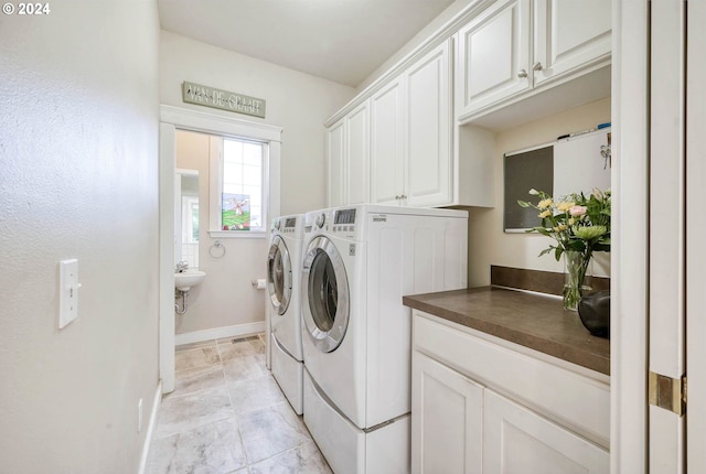 clothes washing area with cabinets and washing machine and dryer