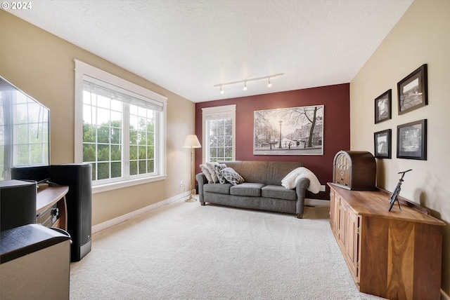 sitting room with rail lighting, light colored carpet, and a textured ceiling