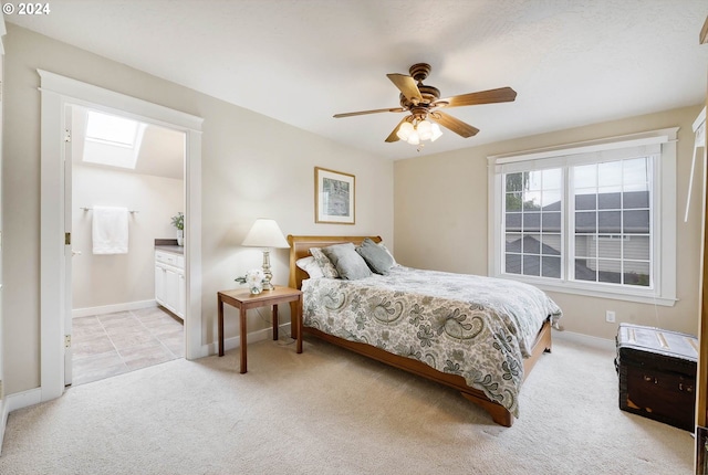 carpeted bedroom with a skylight, ceiling fan, and ensuite bathroom