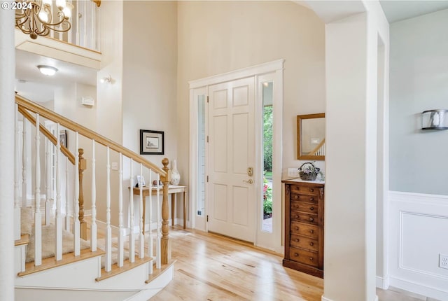 foyer entrance with light wood-type flooring, a high ceiling, and a chandelier