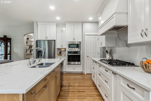 kitchen with premium range hood, appliances with stainless steel finishes, light hardwood / wood-style flooring, and white cabinetry