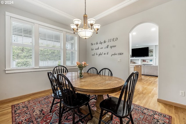 dining area with crown molding, light hardwood / wood-style flooring, and a notable chandelier