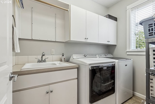 washroom with sink, cabinets, and separate washer and dryer