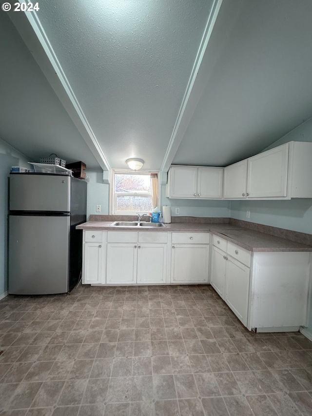 kitchen with white cabinetry, a textured ceiling, sink, and stainless steel fridge