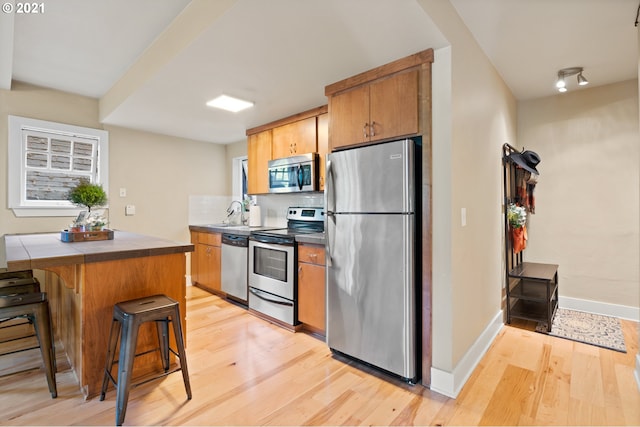 kitchen featuring light wood-type flooring, stainless steel appliances, a breakfast bar, and sink