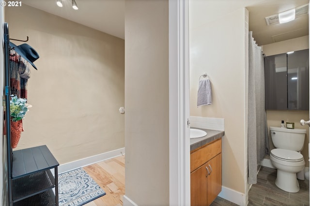 bathroom with wood-type flooring, vanity, and toilet