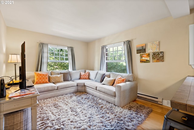 living room with light wood-type flooring, a baseboard heating unit, and a healthy amount of sunlight