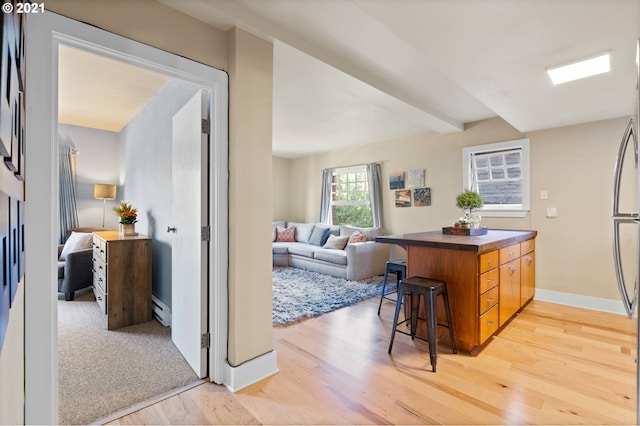 kitchen with a breakfast bar area, baseboard heating, hardwood / wood-style flooring, and kitchen peninsula