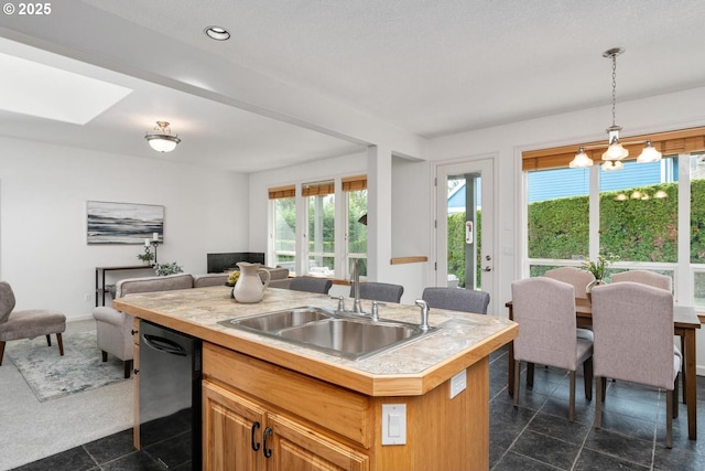 kitchen featuring dishwasher, light countertops, open floor plan, and a sink