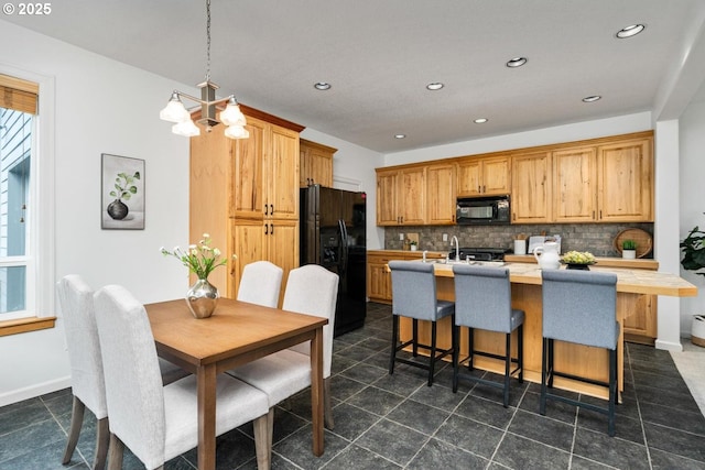 kitchen featuring baseboards, a kitchen island with sink, black appliances, light countertops, and backsplash