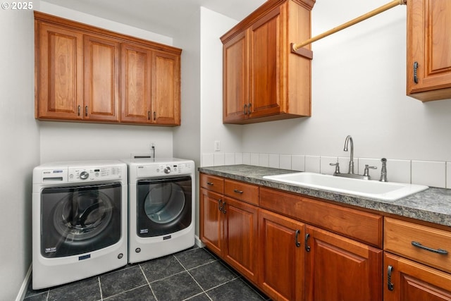 laundry room with cabinet space, washer and dryer, dark tile patterned flooring, and a sink