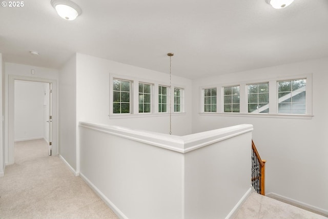 hall with baseboards, an upstairs landing, and carpet