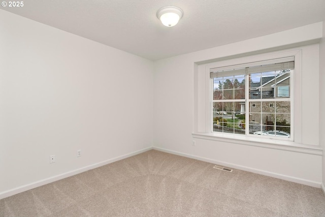 carpeted empty room featuring visible vents and baseboards