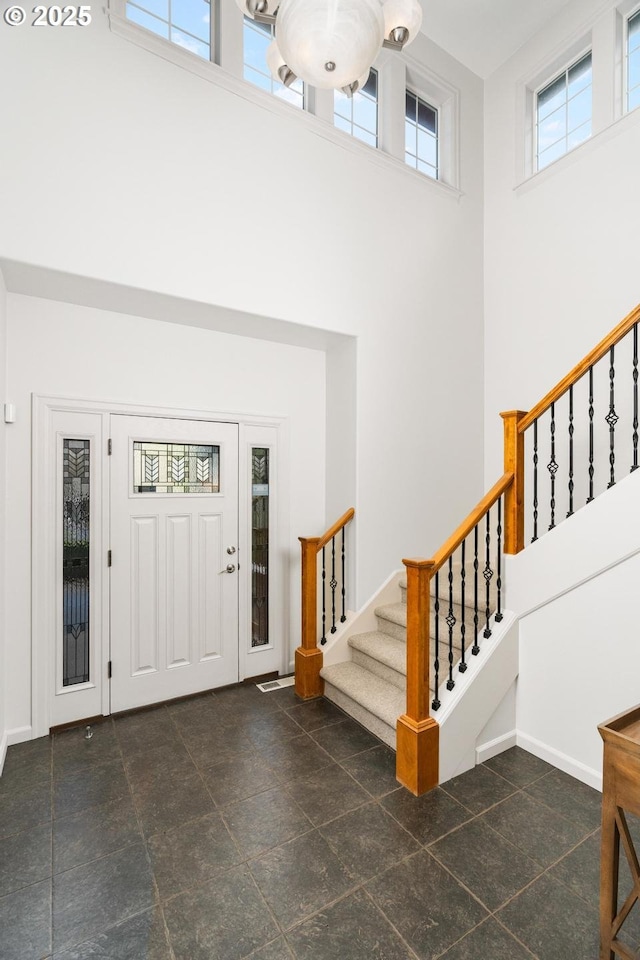 foyer entrance featuring stairway, baseboards, and a high ceiling