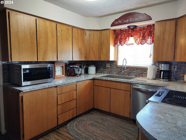 kitchen featuring appliances with stainless steel finishes, dark hardwood / wood-style floors, tasteful backsplash, a textured ceiling, and sink