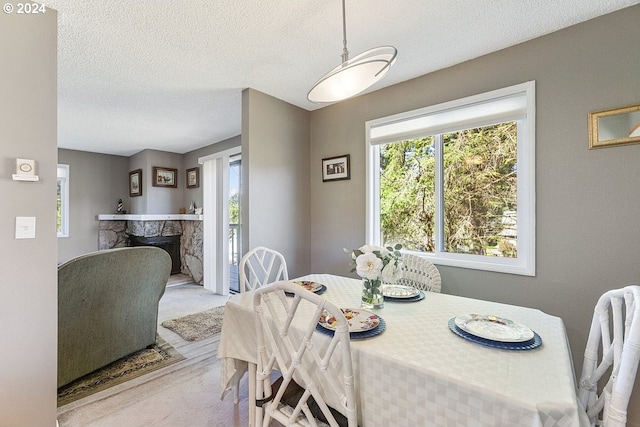 carpeted dining area featuring a textured ceiling and a fireplace