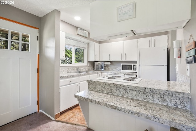 kitchen with white cabinetry, light tile patterned flooring, white appliances, a textured ceiling, and sink