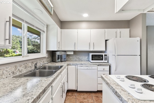 kitchen featuring white appliances, light tile patterned flooring, sink, and white cabinets