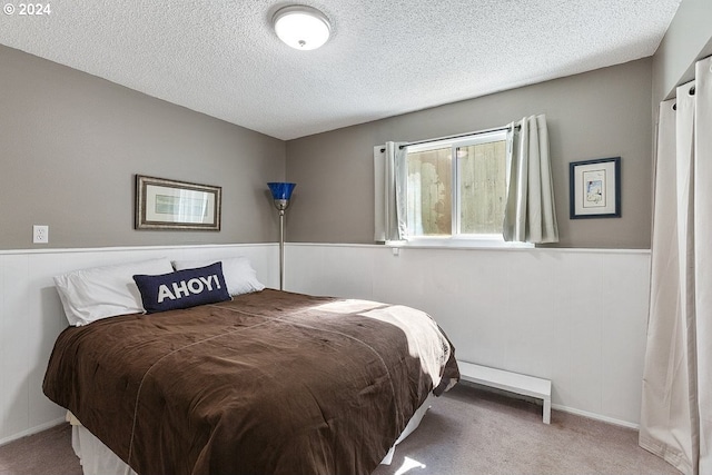 bedroom featuring a textured ceiling and light colored carpet