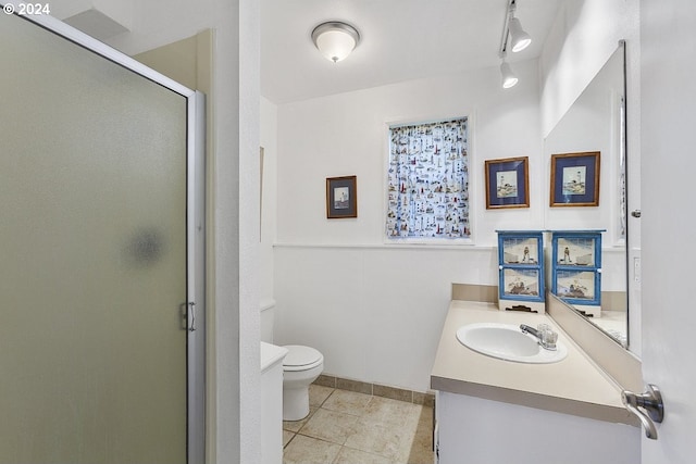 bathroom with vanity, a shower with shower door, track lighting, tile patterned floors, and toilet