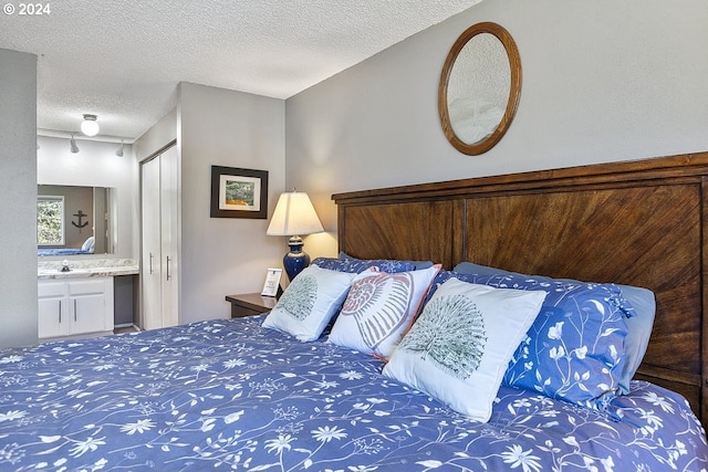 bedroom featuring a textured ceiling, ensuite bath, and sink