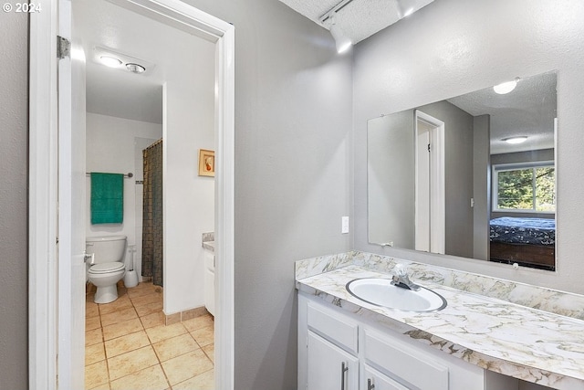 bathroom with vanity, a textured ceiling, tile patterned floors, walk in shower, and toilet