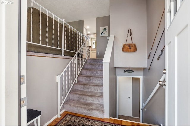 stairs with wood-type flooring and a textured ceiling