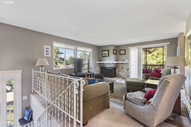 carpeted living room with a textured ceiling, a stone fireplace, and a wealth of natural light