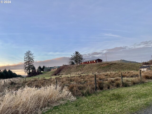 yard at dusk featuring a rural view