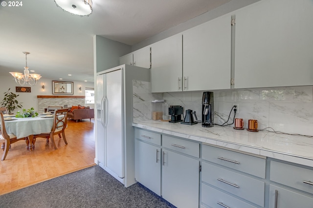 kitchen with backsplash, white fridge with ice dispenser, dark wood-type flooring, pendant lighting, and a chandelier