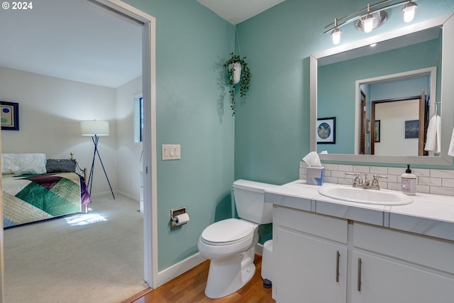 bathroom with backsplash, oversized vanity, hardwood / wood-style flooring, and toilet