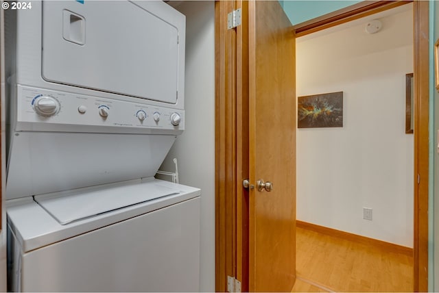 laundry area with light hardwood / wood-style flooring and stacked washing maching and dryer