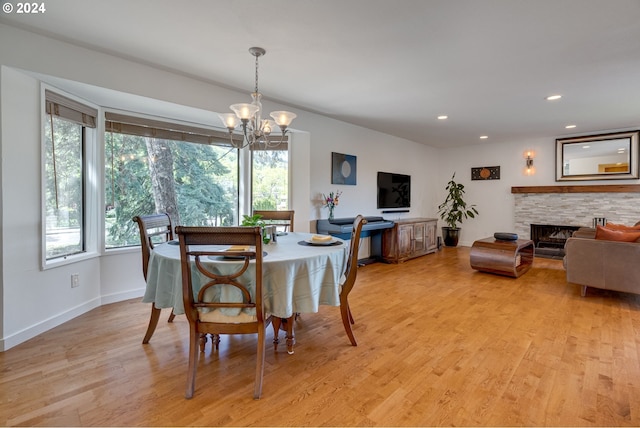 dining area with light hardwood / wood-style flooring, a chandelier, and a fireplace