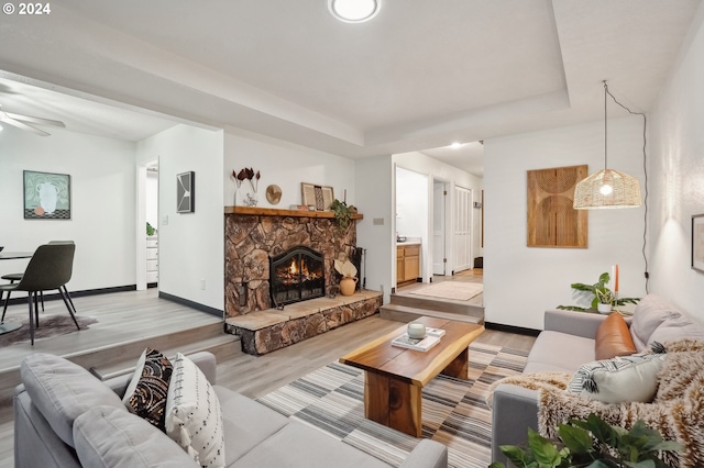 living room with ceiling fan, light hardwood / wood-style floors, and a fireplace