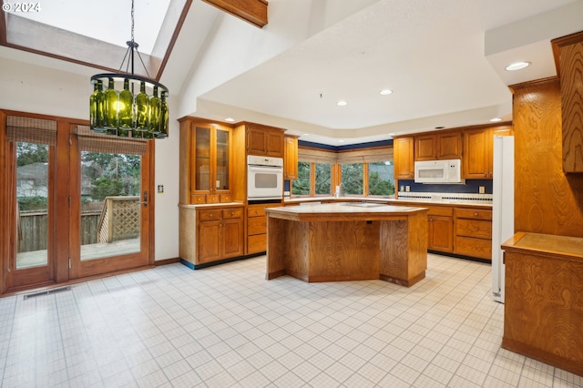 kitchen featuring a center island, an inviting chandelier, lofted ceiling, decorative light fixtures, and white appliances