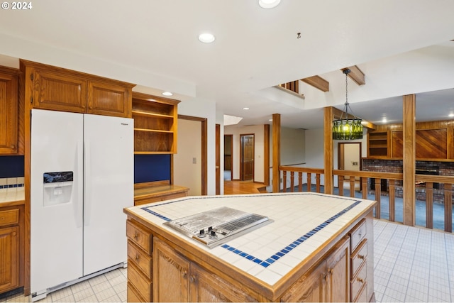 kitchen featuring white refrigerator with ice dispenser, decorative light fixtures, tasteful backsplash, tile counters, and a kitchen island